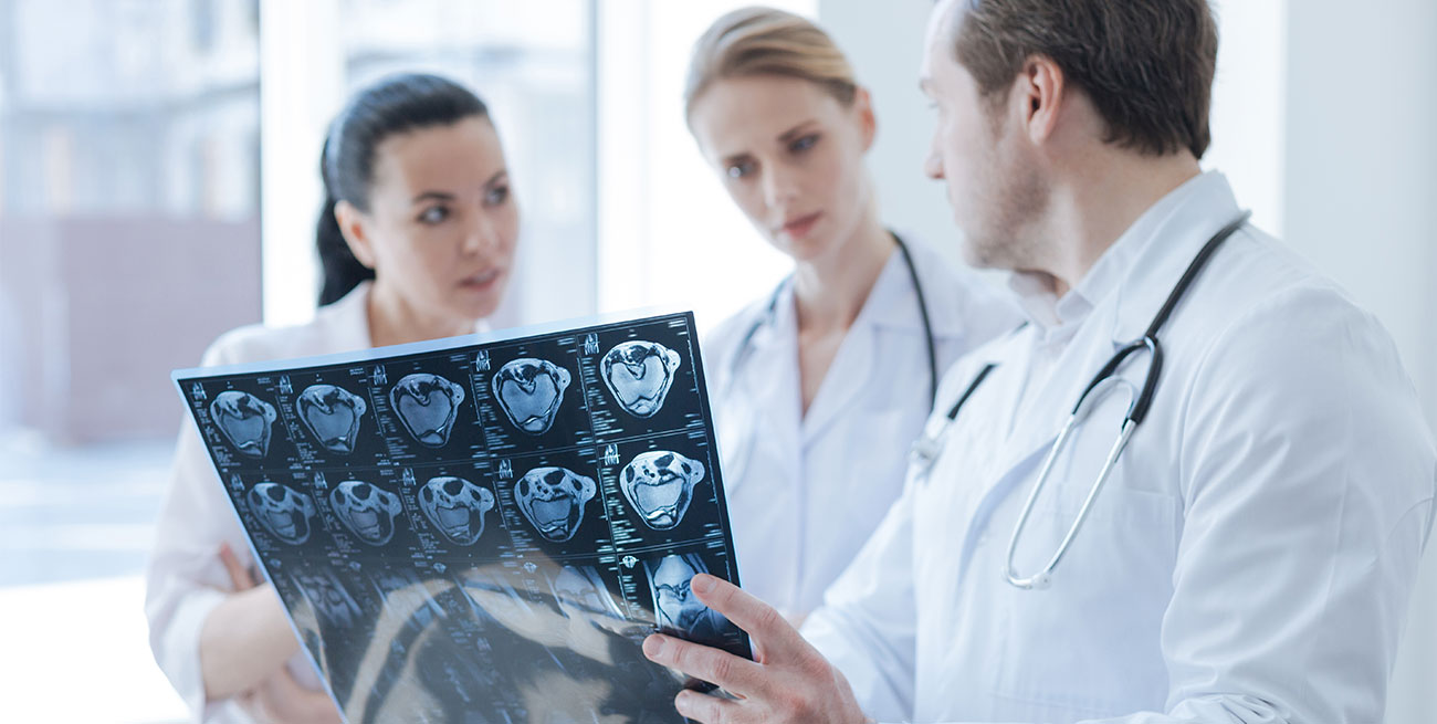 Médico mostra exame raio-x para outras duas colegas médicas