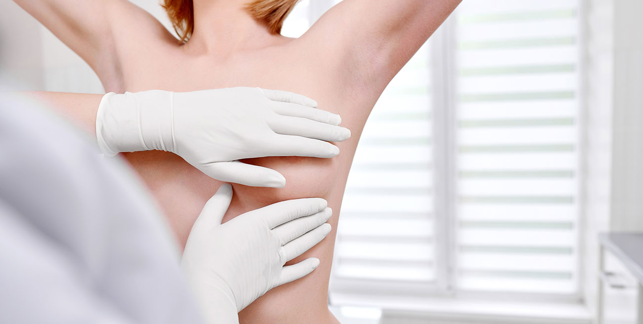 Médico faz exame clínico de mamas de mulher