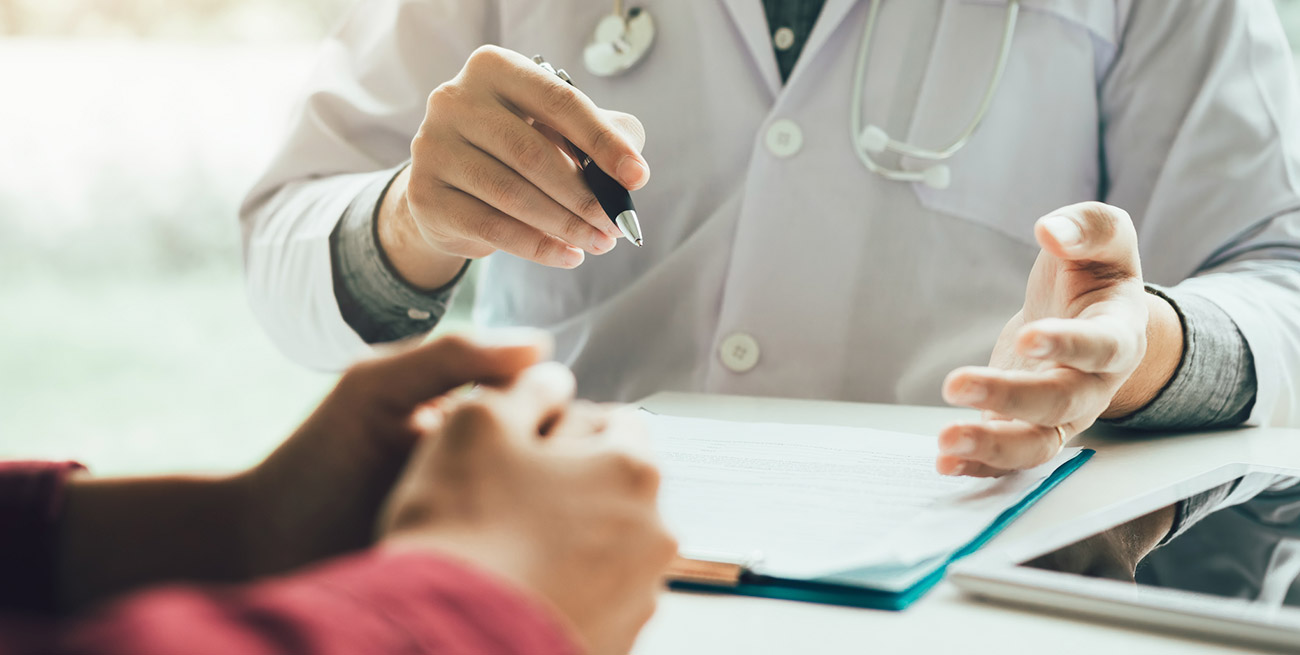 Paciente e médico conversando em mesa de consultório