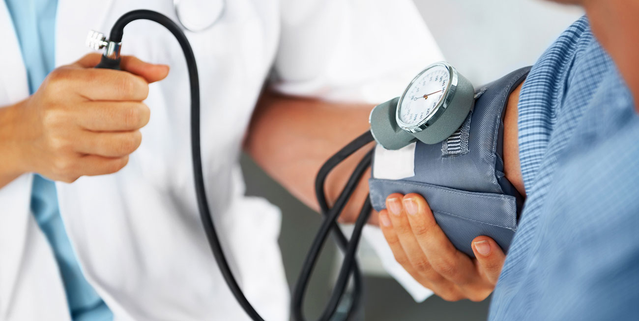 Homem tendo a pressão médida pelo medico
